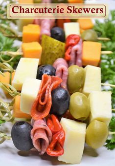 an assortment of cheeses, olives, and meat skewers on a platter