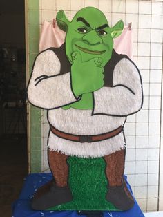 a green man standing in front of a white tiled wall with his hands on his chest