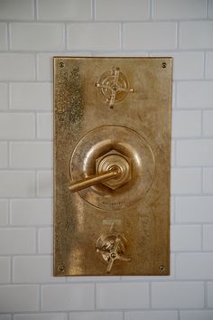 an old fashioned brass faucet mounted to a white tiled wall in a public restroom