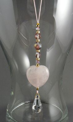 "Rose Quartz Heart Crystal for your car A timeless combination that gives a lift to all life's journeys. Hang this natural Rose Quartz 'Journey of Love' Road Totem from your car's rear view mirror and bring a little more peace and love along the way! Overall length: 8.5 inches. Natural Rose Quartz heart bead is approx. 25mm with 20mm crystal drop at the bottom. Coloured non-stretch nylon cord can be self-looped on car rear-view mirror. Comes with attractive descriptive tag. More CAR CHARMS and C Mirror Crystal, Anting Manik, Car Charms Rear View Mirror, Car Mirror Charm, Car Charms Mirror, Crystal Suncatcher, Rose Quartz Heart, Diy Wire Jewelry, Homemade Jewelry