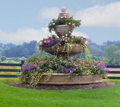 there is a large fountain with flowers growing on it's sides in the grass