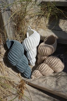 three crocheted slippers sitting in the sand near some tall grass and plants