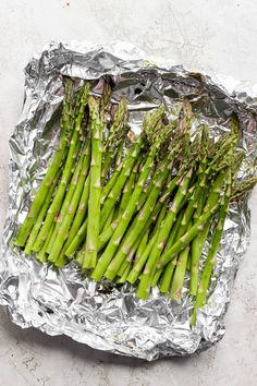 asparagus wrapped in tinfoil on top of a piece of aluminum foil, ready to be cooked