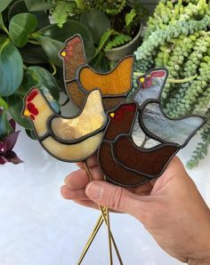 a hand holding three stained glass chickens