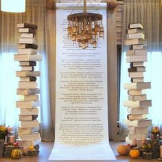 a large stack of books sitting on top of a table next to a chandelier