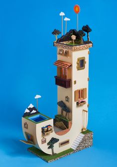 a miniature model of a house made out of paper on a blue background with stairs leading up to the roof