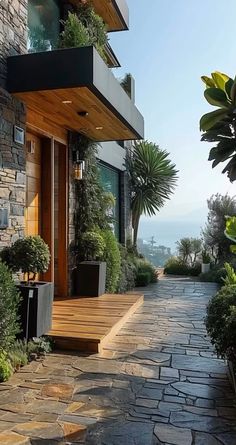 a stone walkway leading to a house with potted plants