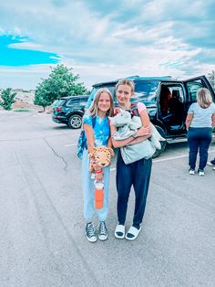 two girls are standing in front of a van with their dog and cat on it