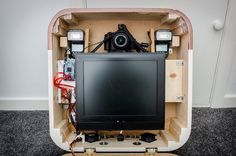 a television sitting inside of a wooden box on top of carpeted floor next to a camera