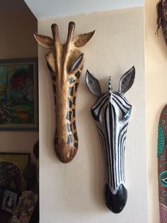 two giraffe head mounted to the side of a wall next to each other