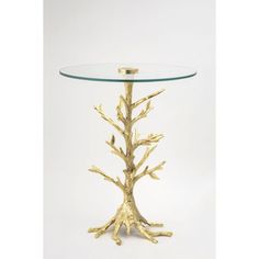 a glass table with gold tree branches on the top and bottom, against a white background