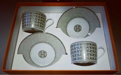 four cups and two saucers in a box with designs on the sides, one is blue and white