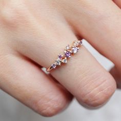 a woman's hand wearing a ring with three different colored stones on the band