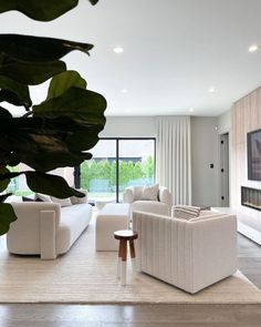 a living room with white couches and a large flat screen tv on the wall