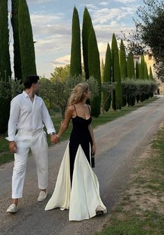 a man and woman walking down a road holding hands