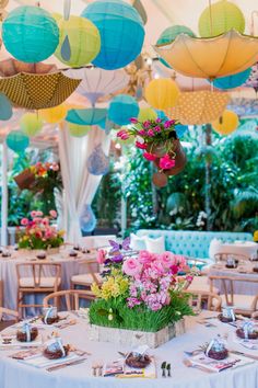 a table with flowers and paper lanterns hanging from the ceiling