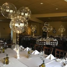 a dining room filled with lots of tables covered in white tablecloths and balloons