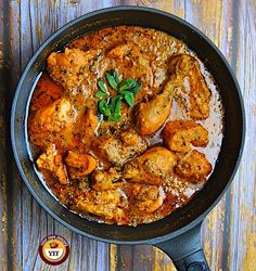 a skillet filled with chicken curry on top of a wooden table