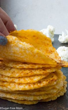 a stack of corn tortillas being held by a woman's hand