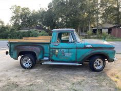 an old green truck parked on top of a dirt field