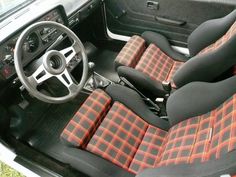 the interior of an old car with red and black plaid cloth upholstered seats