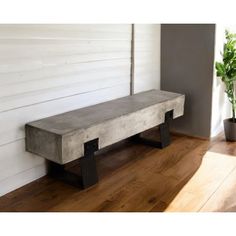 a concrete bench sitting on top of a wooden floor next to a potted plant