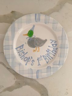 a blue and white plate with a duck on it that says, bristol's 1st birthday