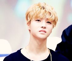 a young man with blonde hair wearing a black t - shirt and gold chain necklace