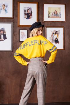 a woman standing in front of pictures wearing a yellow shirt with the words shuffler on it