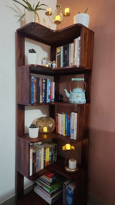 a bookshelf filled with lots of books next to a vase and potted plant