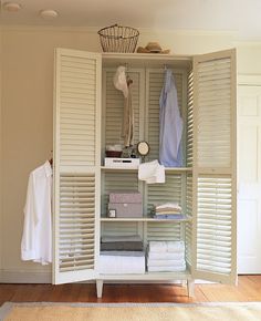 an open closet with white shutters and towels