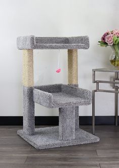 a grey cat tree in the corner of a room next to a vase with flowers