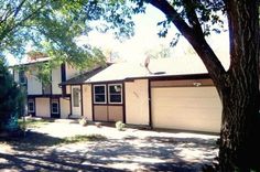 a house with two garages and trees in the front yard