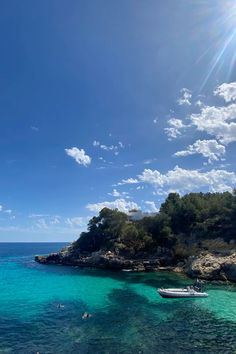 the sun shines brightly over clear blue water with small boats in the foreground