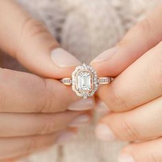 a close up of a person holding an engagement ring with a diamond in the middle