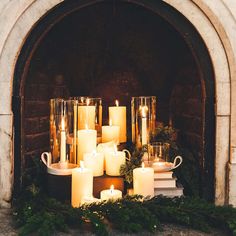 candles are lit in front of a fireplace