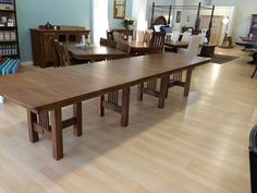 a large wooden table sitting in the middle of a room next to a book shelf