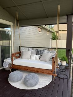 a porch swing with cushions and pillows on it