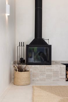 a living room with a fire place next to a basket filled with plants and logs