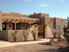 an adobe - style house with cactus trees in front