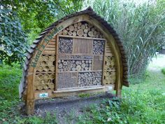 a wooden structure made out of logs in a park with trees and grass around it