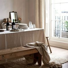 a wooden bench sitting in front of a table with plates and glasses on top of it