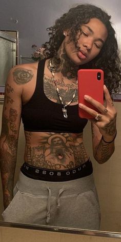 a woman with tattoos taking a selfie in the mirror while holding a cell phone