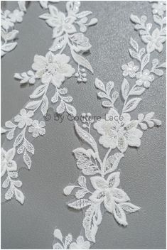 white lace with flowers and leaves on grey background, closeup photo for wedding dress or bridal gown