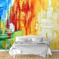 a bed sitting in front of a colorful painting on the wall next to a wooden floor