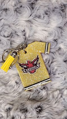 a yellow keychain with a tag on it that says teamhawks and has a tassel attached to it