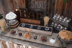 an outdoor dessert bar with marshmallows, chocolate and other treats on it