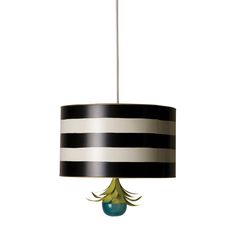 a black and white striped lamp shade with a green flower on the bottom, hanging from a metal rod