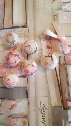 an arrangement of pink flowers and ribbons on a table with other items in the background