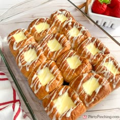 a tray filled with pastries covered in white icing and topped with strawberries